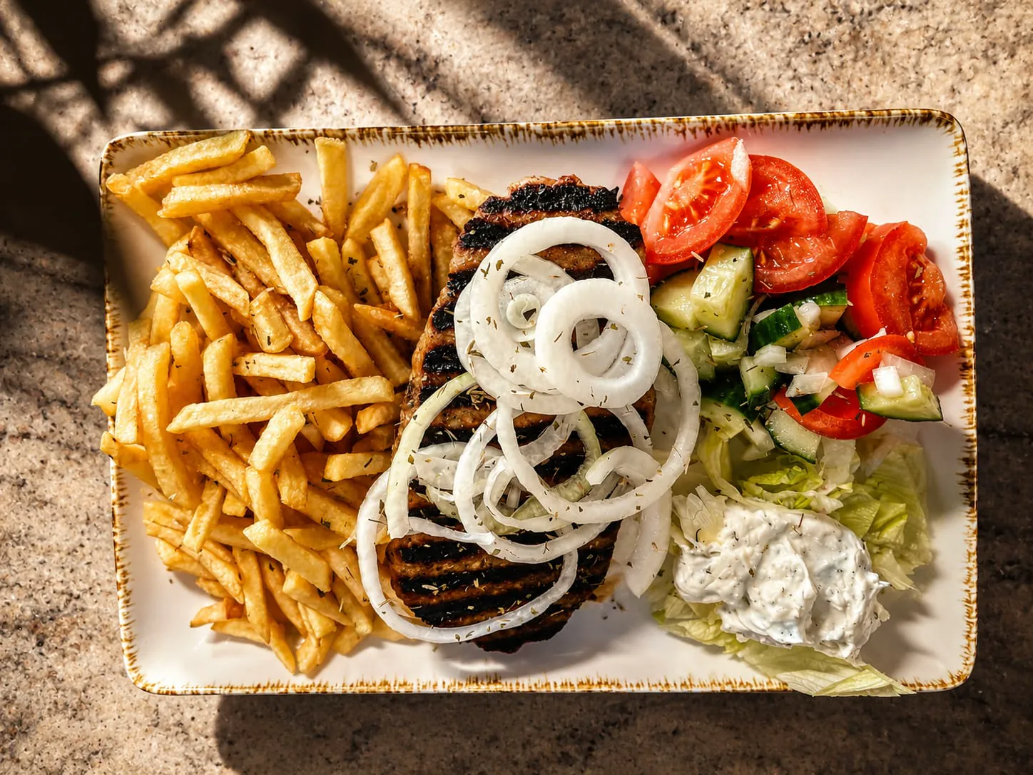 Bifteki mit Pommes, Zwiebelringen, Tomaten-Gurken-Salat und Zaziki
