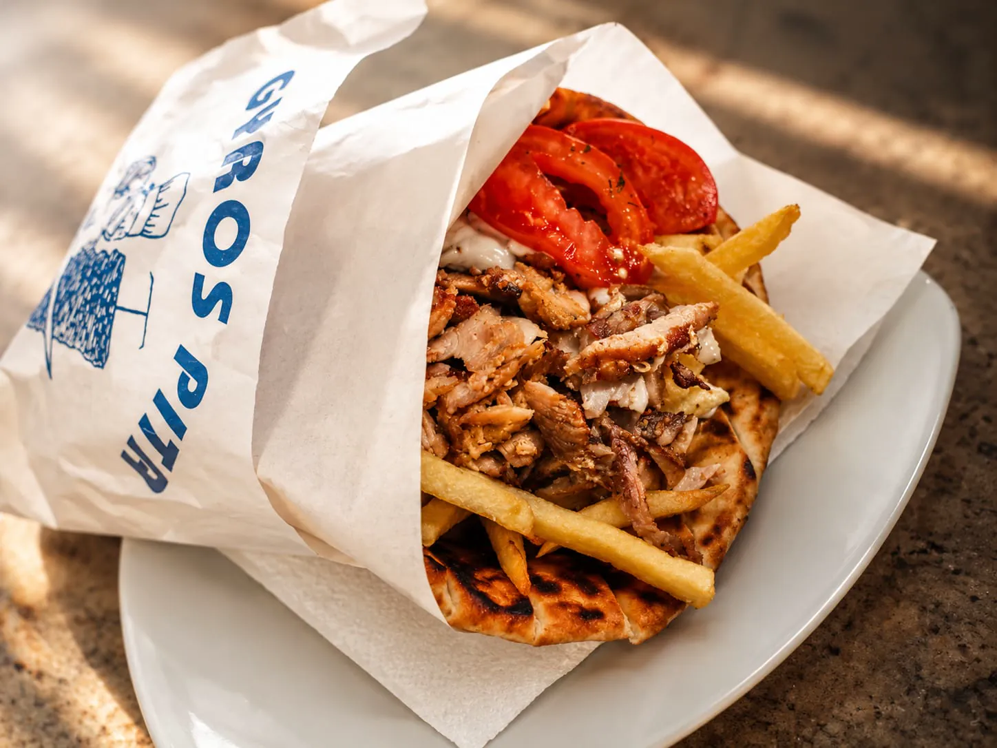 Gyros Pita Special in der Papiertüte mit Tomaten, Zaziki und Pommes